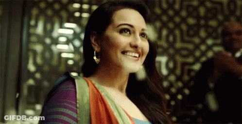 A Woman In A Colorful Dress Is Smiling In Front Of A Man In A Suit . GIF