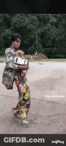 A Woman In A Colorful Outfit Is Holding A Dog In Her Arms .. GIF