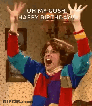 A Woman In A Colorful Sweater Is Raising Her Arms In The Air . GIF