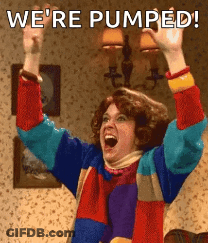 A Woman In A Colorful Sweater Is Raising Her Arms In The Air With The Words We 'Re Pumped Written Above Her GIF