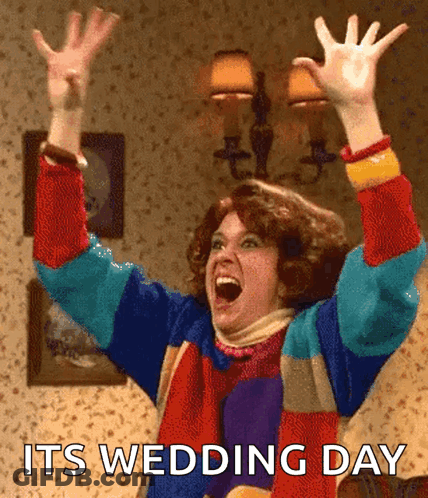 A Woman In A Colorful Sweater With Her Arms In The Air And The Words Its Wedding Day Below Her GIF