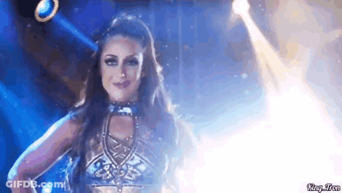 A Woman In A Costume Is Dancing On A Stage In Front Of A Spotlight . GIF