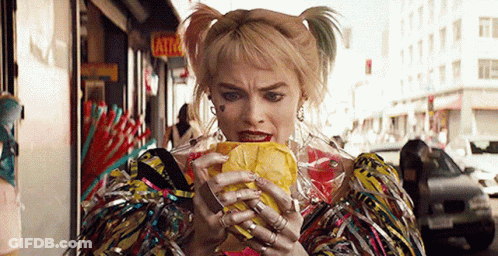 A Woman In A Costume Is Eating A Sandwich On The Street . GIF