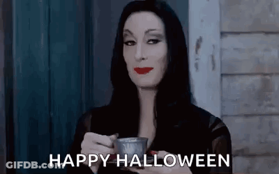 A Woman In A Costume Is Holding A Cup Of Coffee And Saying `` Happy Halloween '' . GIF