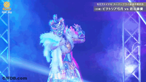 A Woman In A Costume Is On A Stage In Front Of A Sign That Says #Qw Img GIF