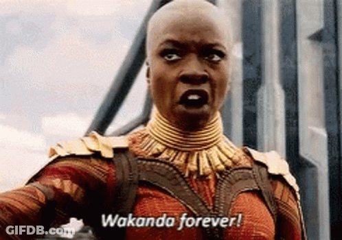 A Woman In A Costume Is Standing In Front Of A Building And Says Wakanda Forever . GIF