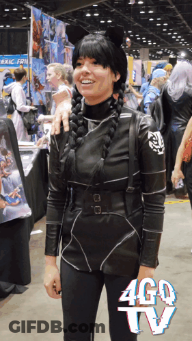 A Woman In A Costume Stands In Front Of A Sign That Says Ago Tv GIF