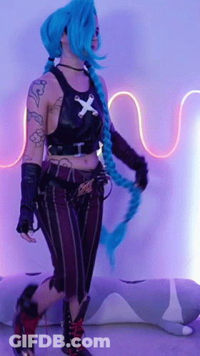 A Woman In A Costume With Blue Hair And A Cross On Her Shirt GIF