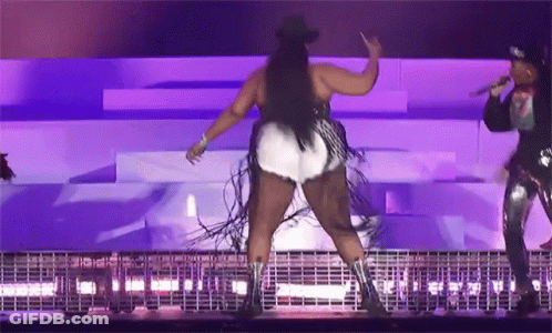 A Woman In A Cowboy Hat Is Dancing On A Stage While Another Woman Sings Into A Microphone GIF
