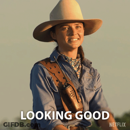 A Woman In A Cowboy Hat Is Smiling With The Words Looking Good Below Her GIF