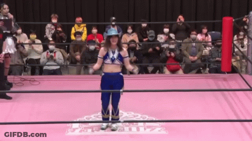 A Woman In A Cowboy Hat Is Standing In A Wrestling Ring In Front Of A Crowd GIF