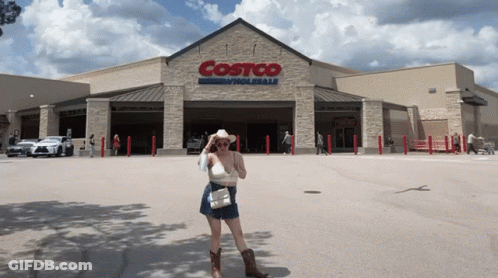 A Woman In A Cowboy Hat Stands In Front Of A Costco Wholesale Store GIF