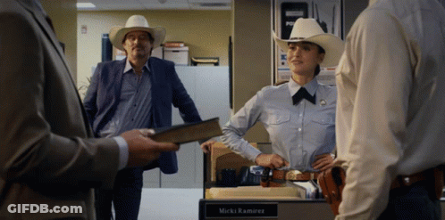 A Woman In A Cowboy Hat Stands In Front Of A Desk With The Name Mark Ramirez Written On It GIF