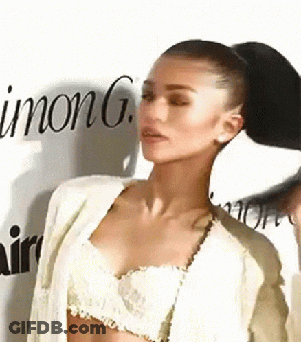 A Woman In A Crop Top And Jacket Is Standing In Front Of A Wall With The Word Inong Written On It . GIF