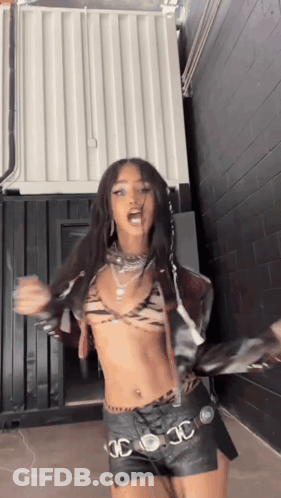 A Woman In A Crop Top And Leather Shorts Is Dancing . GIF