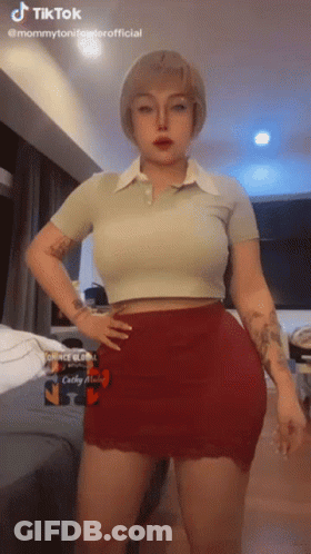 A Woman In A Crop Top And Red Skirt Is Standing With Her Hands On Her Hips . GIF