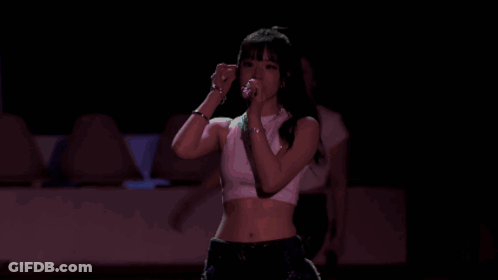 A Woman In A Crop Top Is Dancing On A Stage . GIF