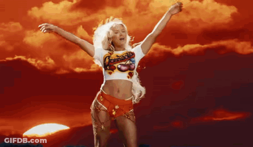 A Woman In A Crop Top Is Dancing With Her Arms Outstretched In Front Of A Sunset . GIF
