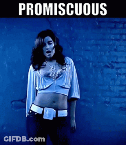 A Woman In A Crop Top Is Standing In Front Of A Brick Wall With Promiscuous Written On It GIF