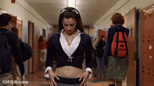 A Woman In A Crop Top Stands In A Hallway With Lockers GIF