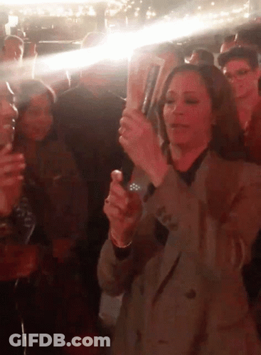 A Woman In A Crowd Holds A Bottle Of Budweiser GIF