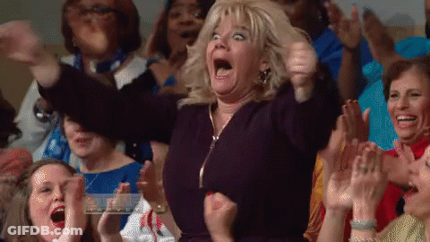 A Woman In A Crowd Of People Is Making A Funny Face . GIF