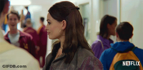 A Woman In A Crowded Hallway With A Netflix Logo In The Corner GIF