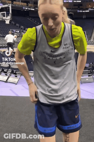 A Woman In A Dallas Wings Jersey Is Standing In A Stadium GIF