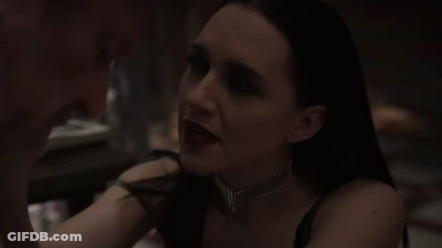 A Woman In A Dark Room Is Looking At Another Woman . GIF