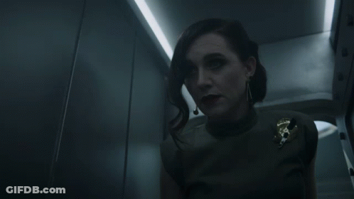 A Woman In A Dark Room With A Badge That Says U.s. Army On It GIF