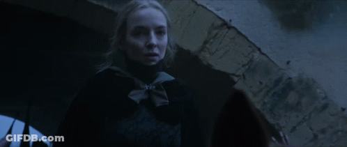 A Woman In A Dark Room With A Brick Wall In The Background GIF