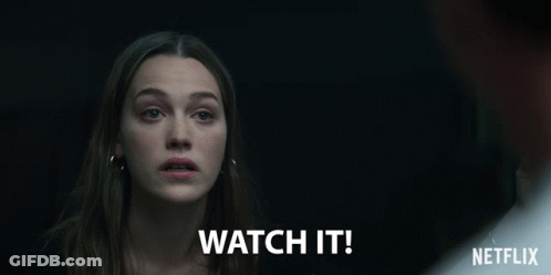 A Woman In A Dark Room With The Words Watch It Written Below Her GIF