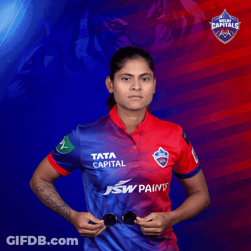 A Woman In A Delhi Capitals Shirt Holds Sunglasses GIF