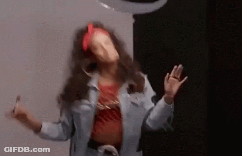 A Woman In A Denim Jacket Is Dancing In A Room . GIF