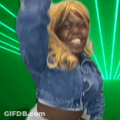 A Woman In A Denim Jacket Is Dancing In Front Of A Green Light GIF