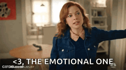 A Woman In A Denim Jacket Is Standing In A Living Room With Her Arms Outstretched And Says The Emotional One . GIF