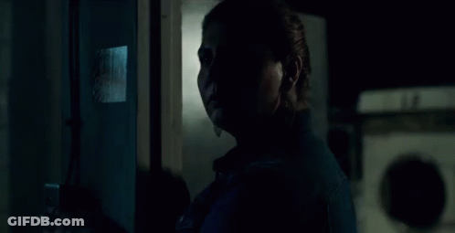 A Woman In A Denim Jacket Stands In Front Of A Fire Extinguisher GIF