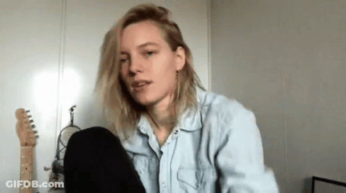 A Woman In A Denim Shirt Is Sitting In Front Of A Microphone In A Room . GIF