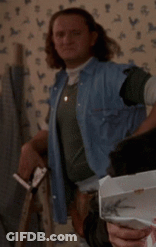 A Woman In A Denim Vest Is Standing In Front Of A Wall With Chickens On It GIF