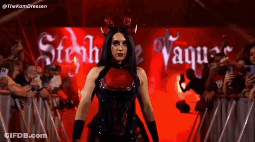 A Woman In A Devil Costume Is Walking In Front Of A Crowd . GIF