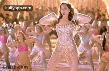 A Woman In A Dress Is Dancing In Front Of A Group Of Dancers . GIF