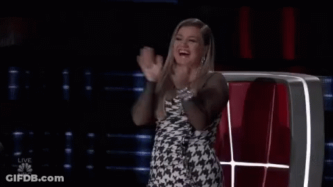 A Woman In A Dress Is Sitting In A Chair And Clapping Her Hands . GIF