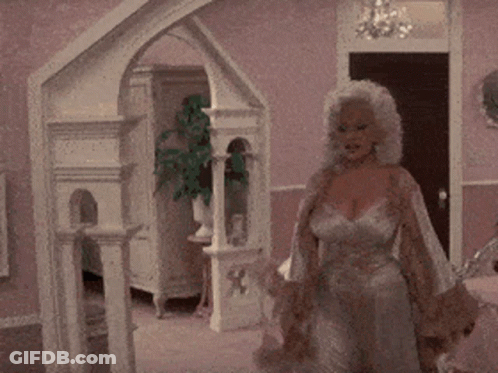 A Woman In A Dress Is Standing In A Room GIF