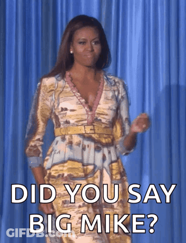 A Woman In A Dress Is Standing In Front Of A Blue Curtain And Asking Did You Say Big Mike GIF