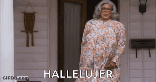 A Woman In A Dress Is Standing In Front Of A Door With The Word Hallelujar Written On It . GIF