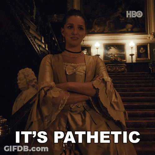 A Woman In A Dress Is Standing In Front Of A Staircase With The Words " It 'S Pathetic " Behind Her GIF