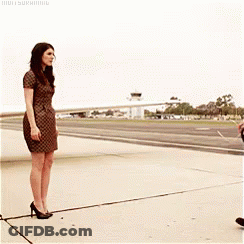 A Woman In A Dress Is Standing Next To A Man On A Runway GIF