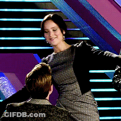 A Woman In A Dress Is Standing Next To A Man On A Set Of Stairs GIF