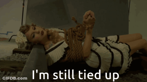 A Woman In A Dress Is Tied Up And Says I 'M Still Tied Up Below Her GIF