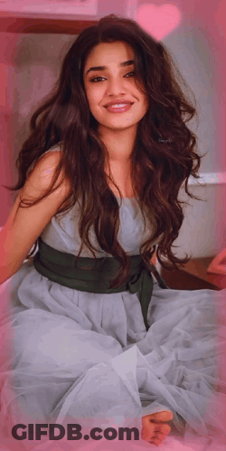 A Woman In A Dress With A Green Belt Around Her Waist Smiles For The Camera GIF
